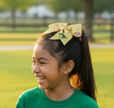 Young girl wearing gold glitter with green gator eye grosgrain River Bluff Gator Eye cheer bow in ponytail with green Gators tee, outdoor lifestyle photo