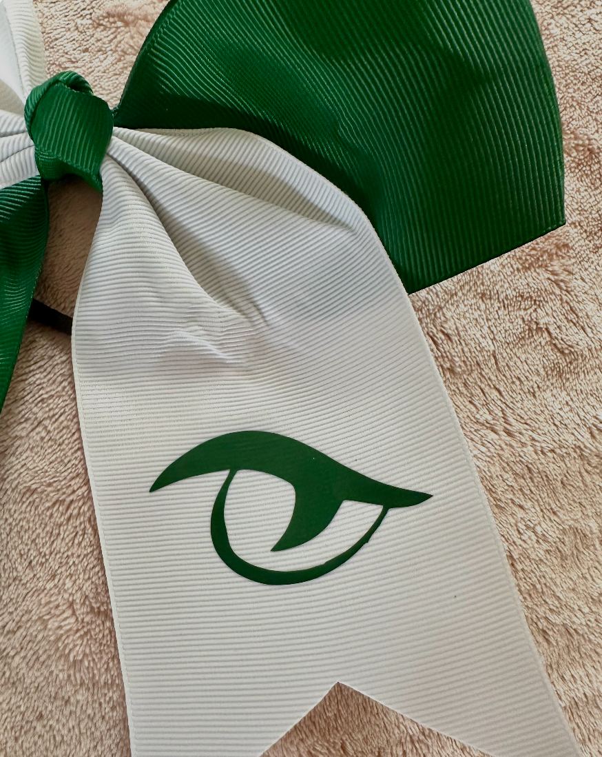 Close-up of forest green Gator Eye vinyl logo on white grosgrain tail of River Bluff cheer bow
