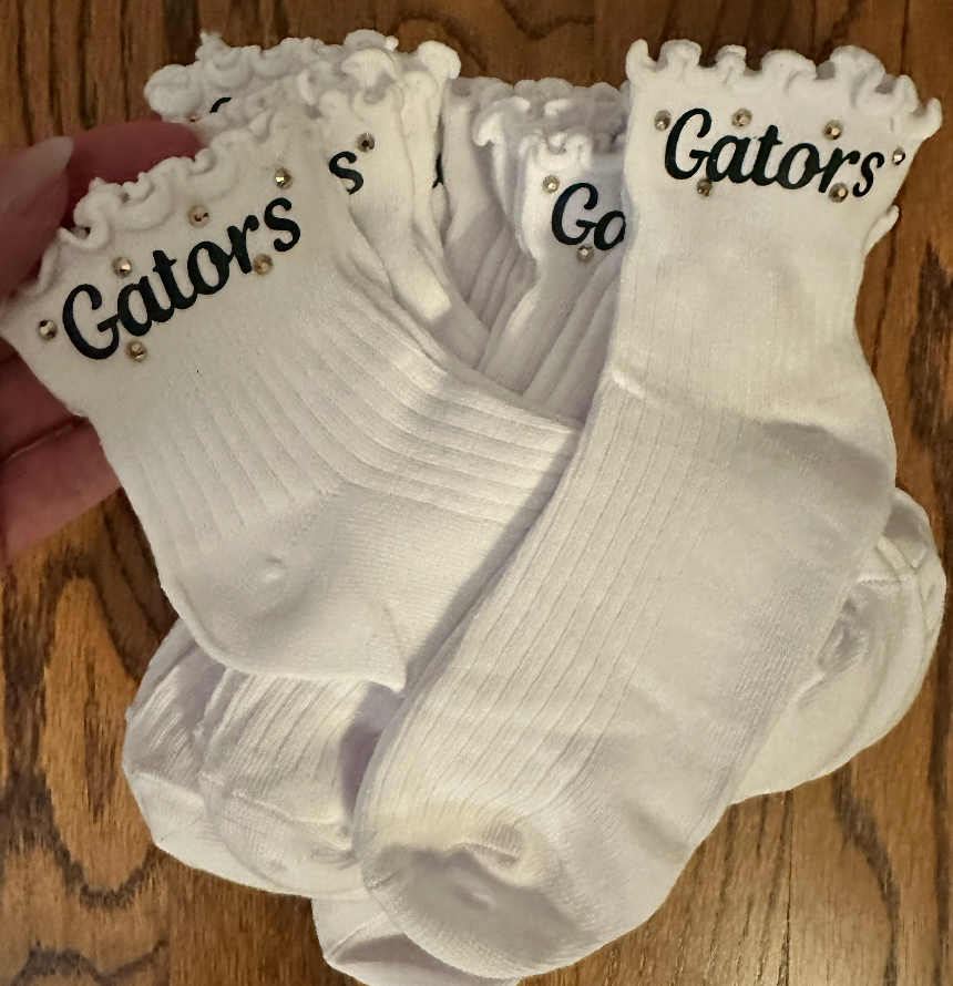 Multiple pairs of white River Bluff Gators frilly ankle socks with gold rhinestone accents – girls cheer spirit wear by Southern Script