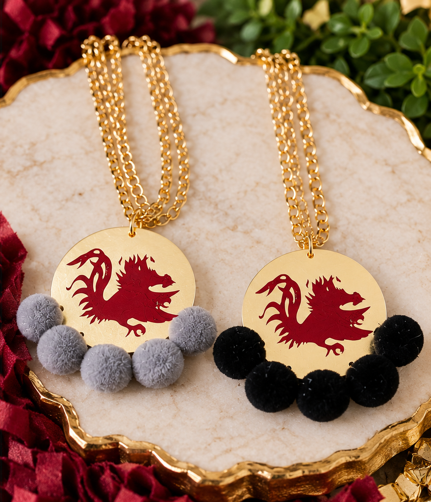 Carolina Gamecock Pom Pom Statement Necklaces by Southern Script showing Black and Gray pom-pom options with garnet Gamecock designs and gold-tone chains.