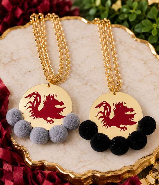 Carolina Gamecock Pom Pom Statement Necklaces by Southern Script showing Black and Gray pom-pom options with garnet Gamecock designs and gold-tone chains.