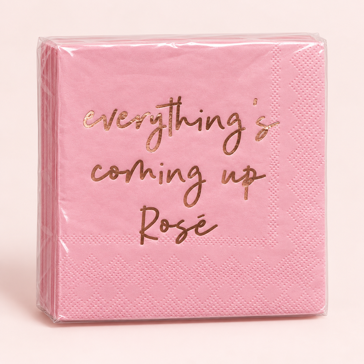 A stack of pink paper napkins wrapped in clear plastic, featuring the phrase 'everything's coming up Rosé' printed in metallic rose gold script on the front.