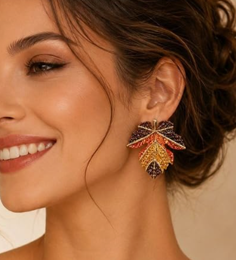 Model wearing a multicolor maple leaf dangle earring with brown, orange, and gold-tone details